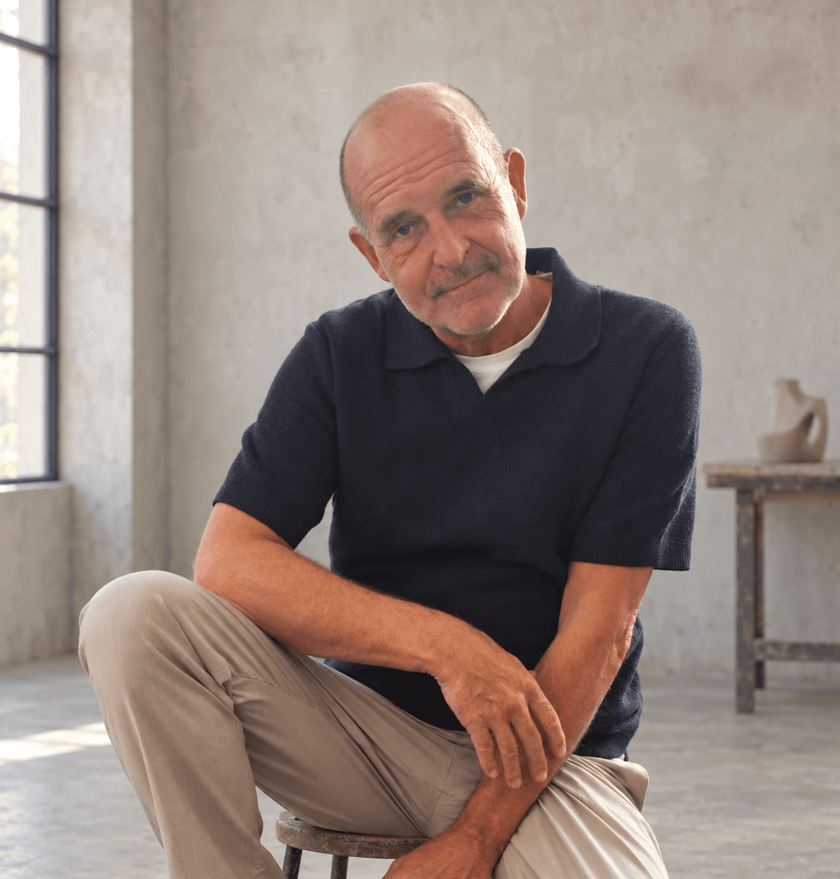 Eric Stevens seated in a quiet industrial atelier, with an AI-edited setting